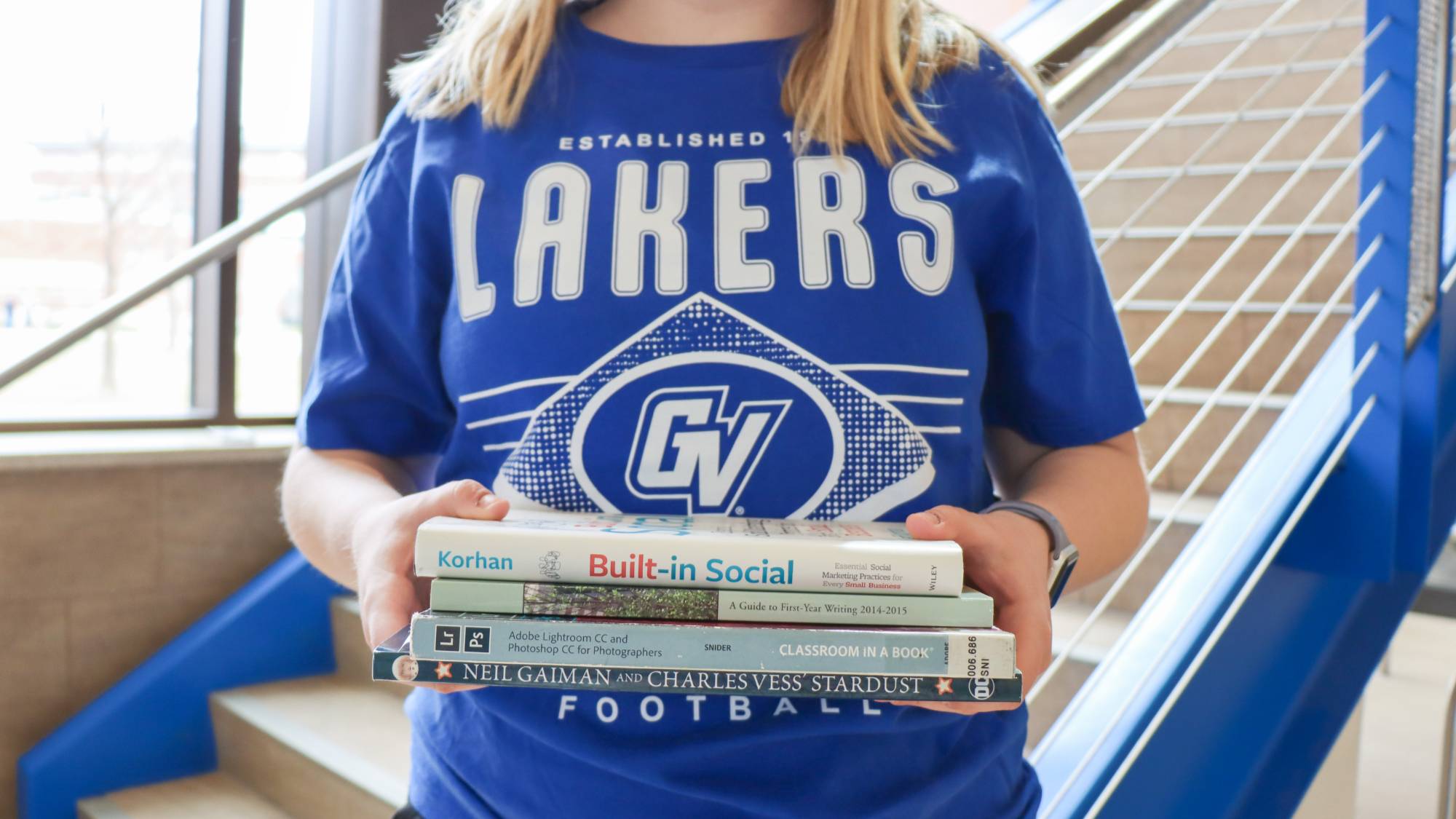 student wearing blue Lakers shirt and holding textbooks